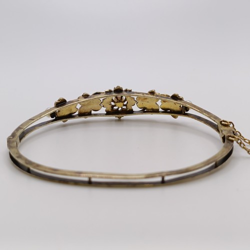 538 - A yellow metal and seed pearl floral bangle