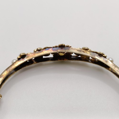 538 - A yellow metal and seed pearl floral bangle