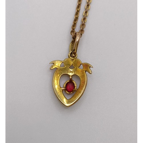 561 - A 15ct gold, seed pearl and red stone heart shaped pendant, on a 9ct gold chain