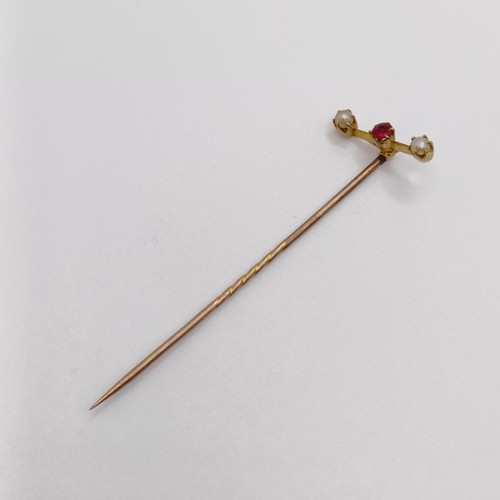 590 - A stick pin, inset with a red coloured stone and seed pearls