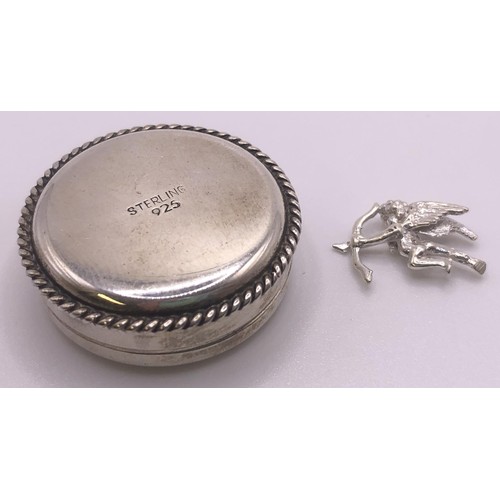 592 - A silver coloured metal pill box, and a small cherub charm (2)