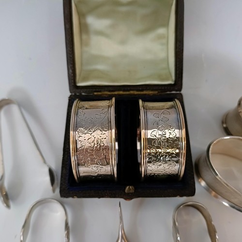 59 - A pair of silver napkin rings, cased, another pair of silver napkin rings, and four pairs of sugar t... 