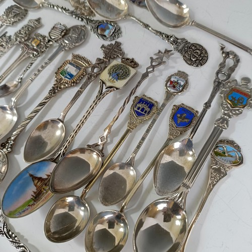 77 - Assorted silver coloured metal and other travel/commemorative spoons, some with enamel decoration