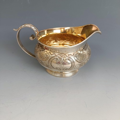 332 - A provincial silver milk jug, with embossed decoration and a gilded interior, 6.8 ozt