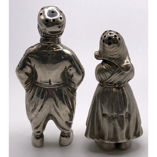 146 - A silver pepperette, in the form of a Dutch boy, 8 cm high, and a similar silver coloured metal pepp... 