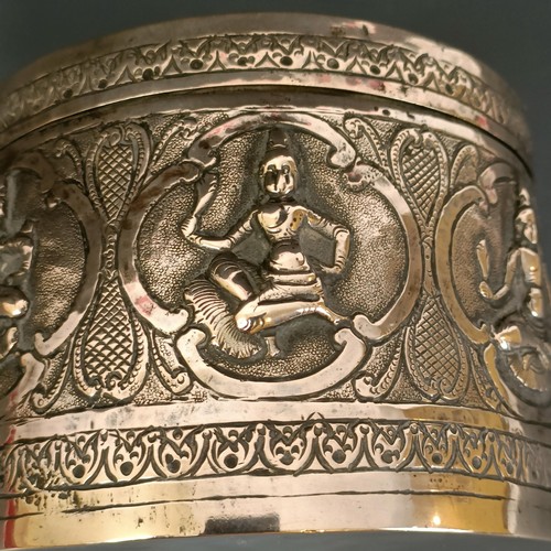 358 - An Indian or Burmese silver coloured metal box and cover, decorated deities, 11 cm diameter