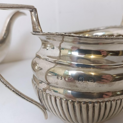 374 - A matched silver three piece tea set, with a reeded lower body, various dates and makers, 35.1 ozt (... 