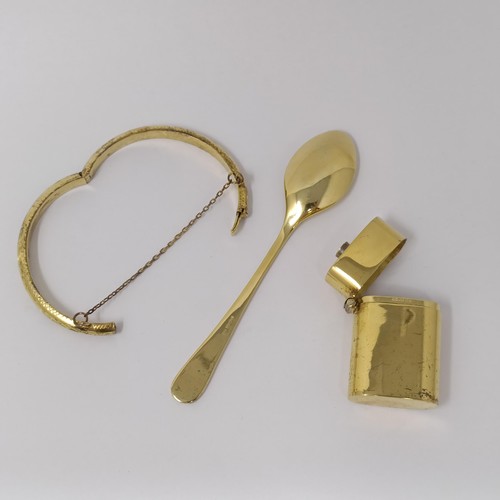 319 - A silver gilt lighter case, a silver gilt teaspoon, and a silver gilt child's bangle (3)