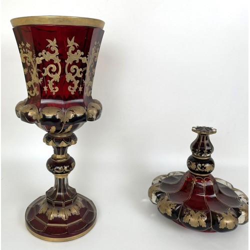 1059 - A large 19th century ruby glass goblet and cover, decorated in gilt, broken and repaired, gilt rubbe... 