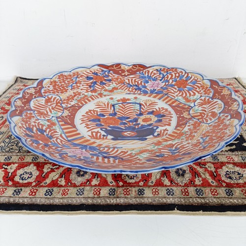 1068 - A Japanese Imari plate, 40 cm diameter, and a silk rug, 64 cm x 46 cm (2)