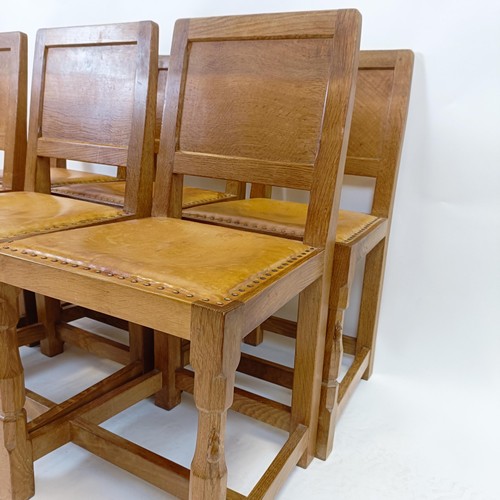 1206 - Robert Mouseman Thompson of Kilburn, a set of six oak panel back dining chairs, with studded leather... 