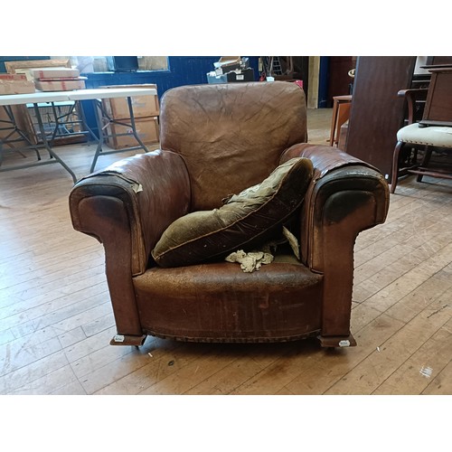 1308 - A 1920s brown leather easy chair, in need of restoration