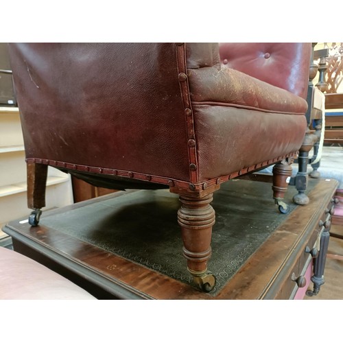 1318 - A late 19th/early 20th century leather button back armchair, on turned mahogany legs, worn, and an o... 