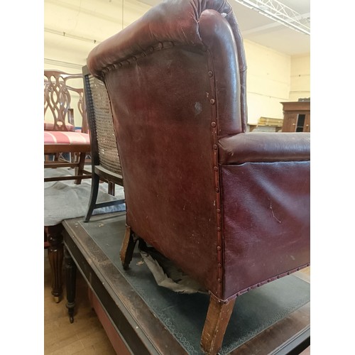 1318 - A late 19th/early 20th century leather button back armchair, on turned mahogany legs, worn, and an o... 