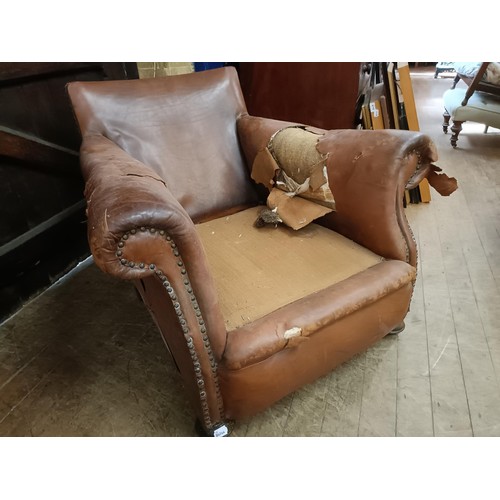 1386 - A 1920s brown leather easy chair, in need of restoration