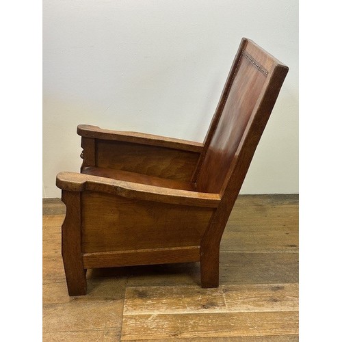 1225 - Robert Mouseman Thompson of Kilburn, a 1920s adzed oak library or smoking chair, having a rare panel... 