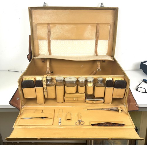 565 - A vintage fitted suitcase, fitted with silver topped bottles, in a canvas case