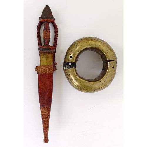 268 - A brass slave shackle, 14 cm diameter, and a dagger in a leather sheath (2)Provenance: Reportedly ow... 