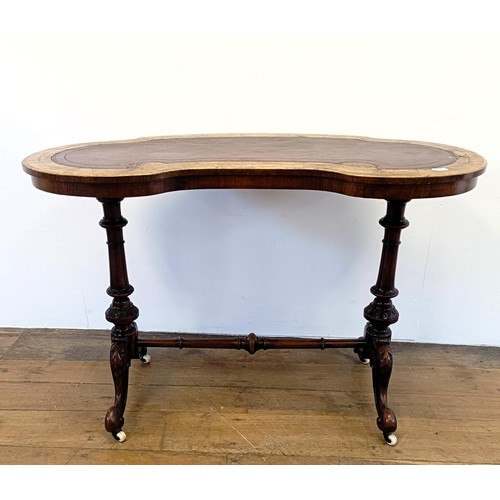 911 - A walnut kidney shaped writing table, with a leather inset top, 104 cm wide