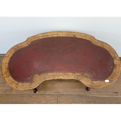 911 - A walnut kidney shaped writing table, with a leather inset top, 104 cm wide