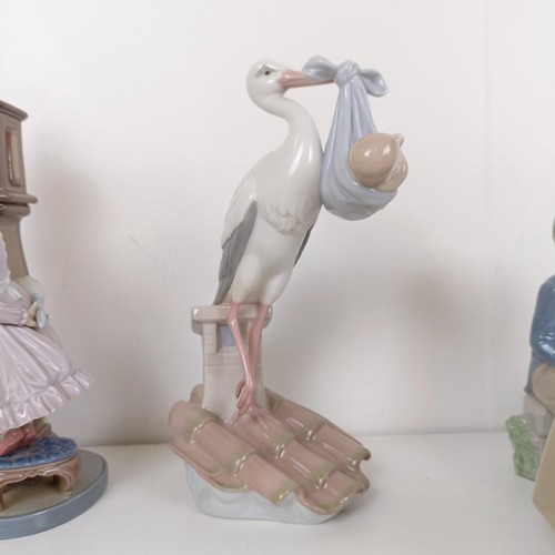 596 - A Lladro figure of a girl cleaning a longcase clock, with a cat on top of the clock, two other Lladr... 