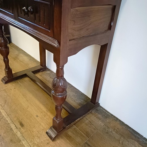 927 - An oak cupboard on stand, having a pair of linen fold panel doors above a drawer, 77 cm wide