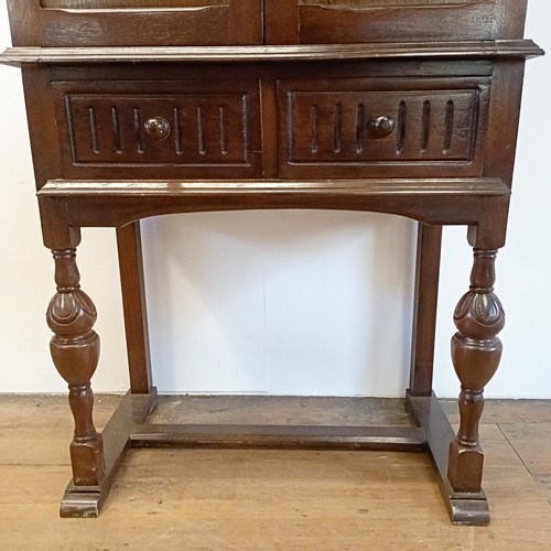 927 - An oak cupboard on stand, having a pair of linen fold panel doors above a drawer, 77 cm wide