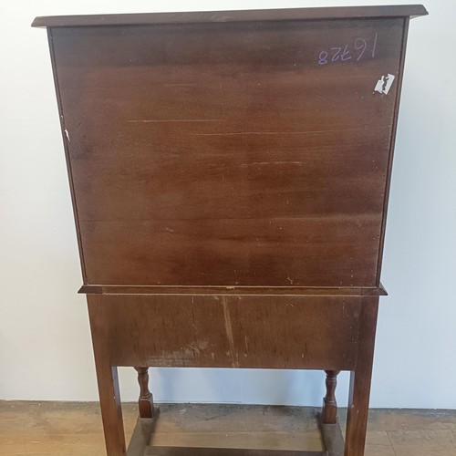 927 - An oak cupboard on stand, having a pair of linen fold panel doors above a drawer, 77 cm wide