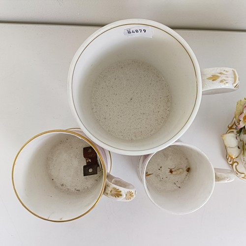 586 - A 19th century floral encrusted vase and cover, 21 cm high, various losses, and three mugs (4)