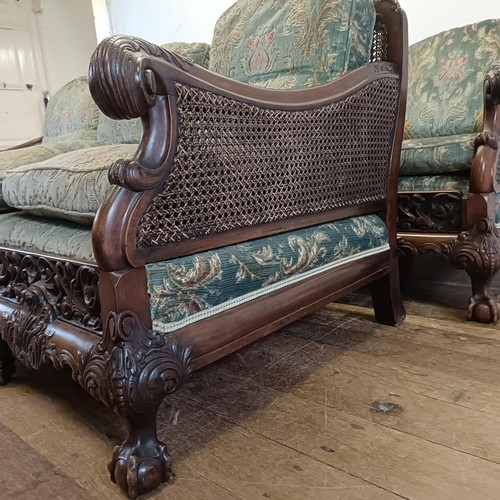 960 - A bergere suite, with a carved mahogany frame, double caned arms and back, some losses, comprising a... 