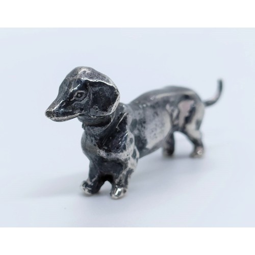 717 - A silver figure of a dachshund, London, 1972, 77g,  6 cm wide, and a continental silver figure of a ... 