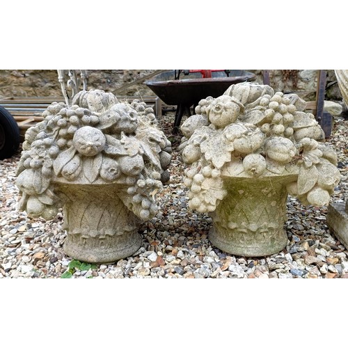 1074 - A pair of composite stone garden finials, in the form of urns of fruit, 40 cm diameter