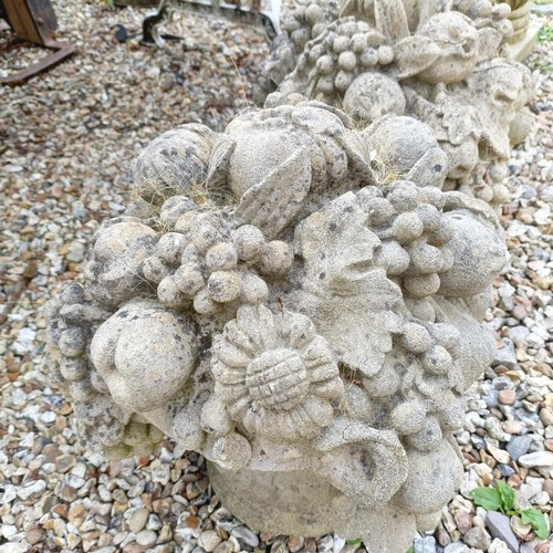 1074 - A pair of composite stone garden finials, in the form of urns of fruit, 40 cm diameter