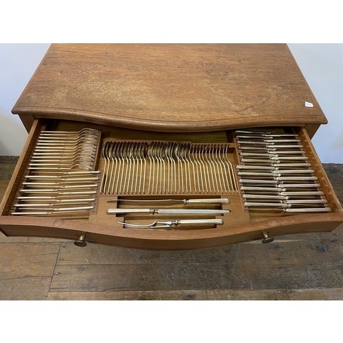 975 - A silver plated canteen of cutlery, settings for twelve, in an oak serpentine two drawer table, 97 c... 