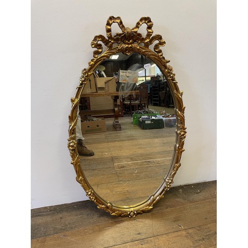 1061 - A gilt framed oval mirror, with a bow finial