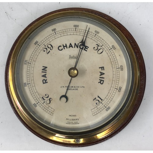 858 - A ship's barometer, by J N Taylor & Co, Adelaide, in a brass case with a mahogany mount, 24 cm d... 