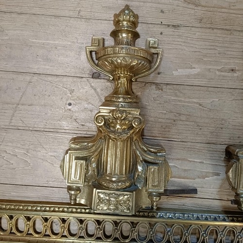 1070 - A gilt metal fender, with urn finials, 124 cm wide