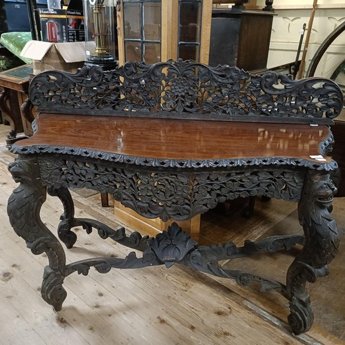 973 - A Burmese serpentine front table, profusely carved with foliate and animal forms, 135 cm wide