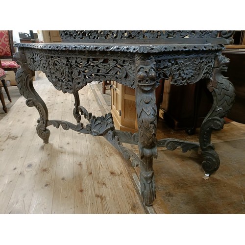 973 - A Burmese serpentine front table, profusely carved with foliate and animal forms, 135 cm wide