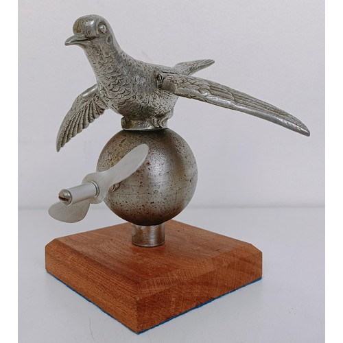 472 - A rare and unusual mechanical racing pigeon car mascot, with a later propeller, mounted on wooden ba... 