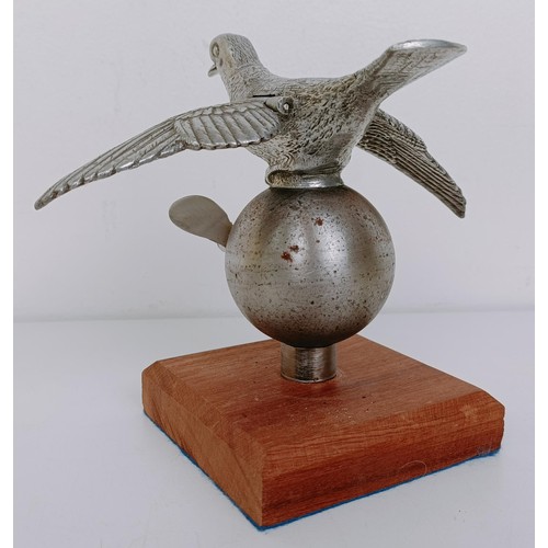 472 - A rare and unusual mechanical racing pigeon car mascot, with a later propeller, mounted on wooden ba... 