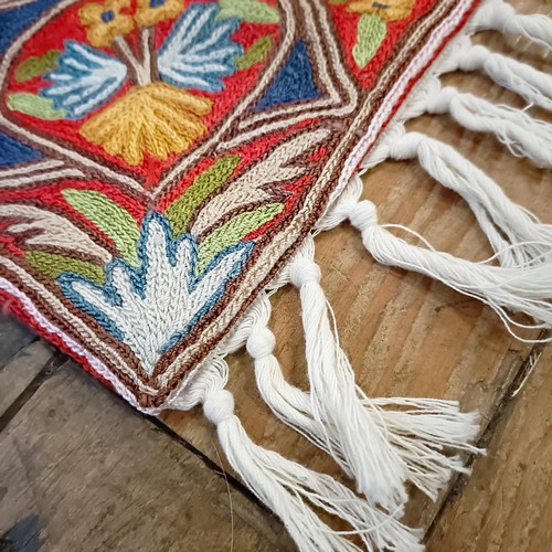 809 - A crewelwork rug, decorated flowers, 146 x 86 cm Provenance: Sold on behalf of the SNCB Society