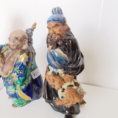 823 - A Chinese figure of a man in a robe, 20 cm high, and two other figures (3)