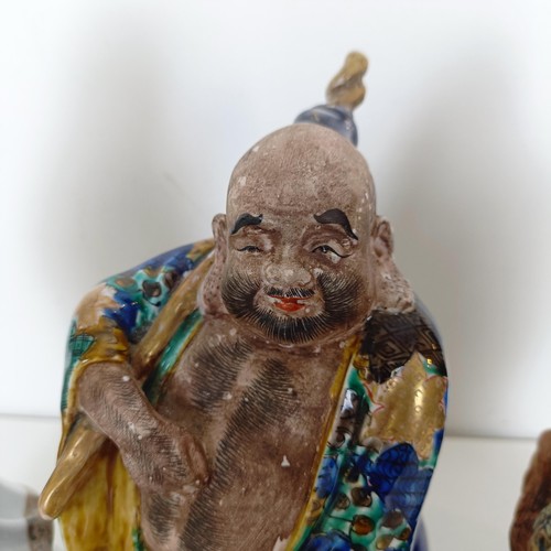 823 - A Chinese figure of a man in a robe, 20 cm high, and two other figures (3)