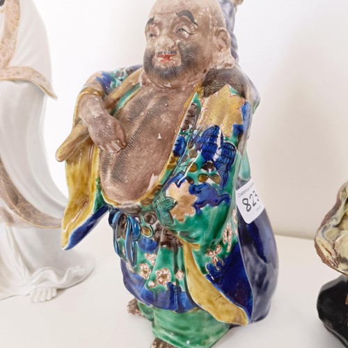 823 - A Chinese figure of a man in a robe, 20 cm high, and two other figures (3)