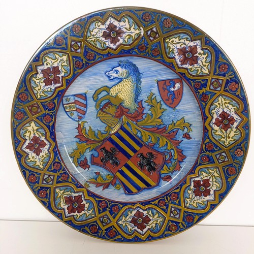 824 - A majolica charger, decorated crest, with a floral border, signed verso, 40 cm diameter