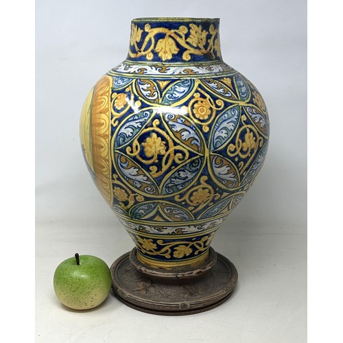 887 - A late 16th century Faience pharmacy jar, decorated saint, with a carved wooden base, 40 cm