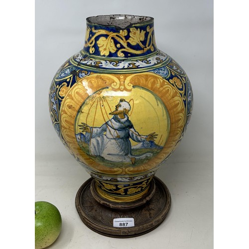 887 - A late 16th century Faience pharmacy jar, decorated saint, with a carved wooden base, 40 cm