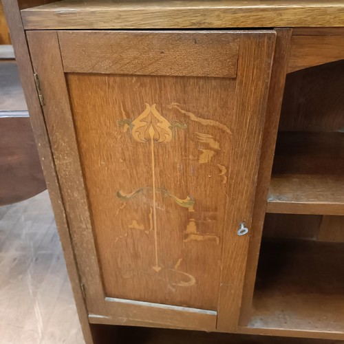 1049 - An Art Nouveau style oak bookcase, with a pierced top rail, above shelves and two cupboard doors, in... 