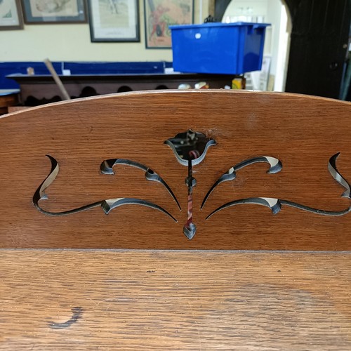 1049 - An Art Nouveau style oak bookcase, with a pierced top rail, above shelves and two cupboard doors, in... 